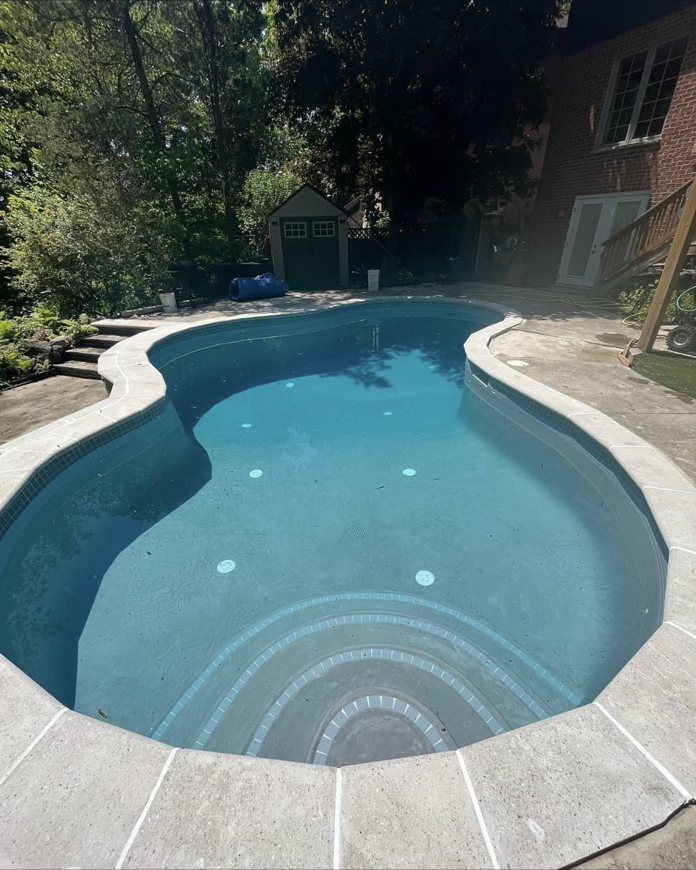 Same freeform pool after renovation with a new finish, step tile and coping